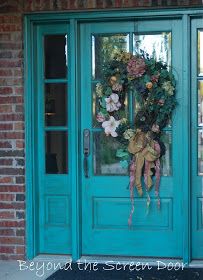 a blue door with a wreath on the front and side glass doors that have flowers in them