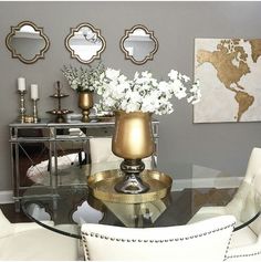 a dining room table with white chairs and gold accents