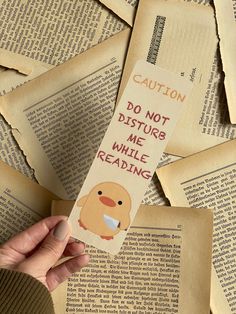 someone is holding up a bookmark that reads caution do not disturb me while reading