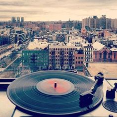 an old record player on top of a building with city in the backround