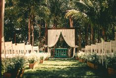 an outdoor ceremony with white chairs and drapes