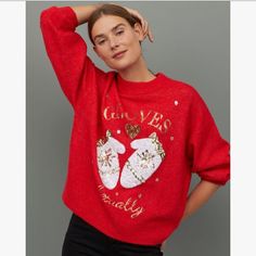 a woman wearing a red christmas sweater and black pants with her hands on her head