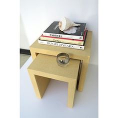 a stack of books sitting on top of a wooden table next to a glass vase