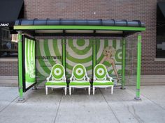 three green and white chairs sitting in front of a booth on the side of a street