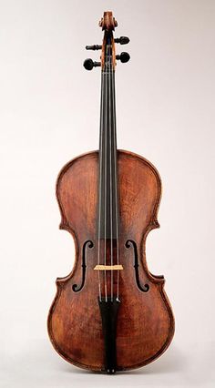 an old violin sitting on top of a white table next to it's back end