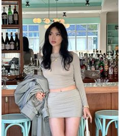 a woman standing in front of a bar holding a purse and looking at the camera