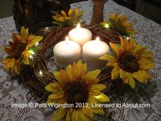 three candles are placed in a wreath with sunflowers on a doily table