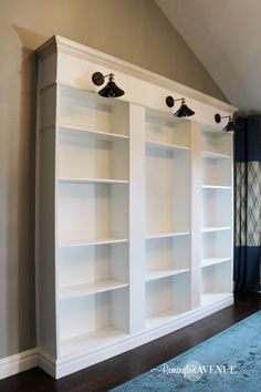 a living room with white bookcases and blue rug on the floor in front of it