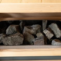 some rocks are in a metal container on a wooden shelf next to a wood table