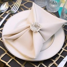 a white plate topped with a napkin next to silver utensils and glassware