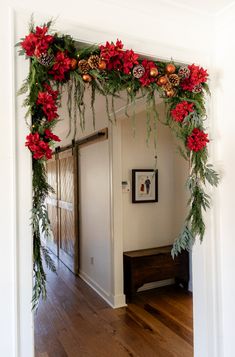 a hallway decorated for christmas with red poinsettis and pine cones on the garland