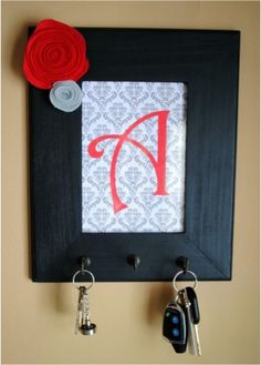 a black frame with red letters and two keys hanging from it's hooks on a wall