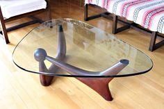 a glass table sitting on top of a hard wood floor next to a red and white chair