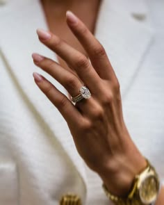 a close up of a person's hand with a diamond ring on her finger