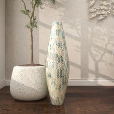 two vases sitting next to each other on top of a wooden floor in front of a wall