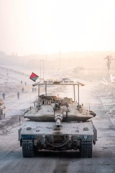 an army tank driving down a dirt road