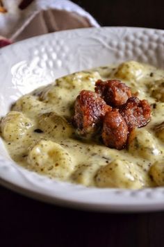 a white bowl filled with food covered in gravy and sauce on top of a wooden table