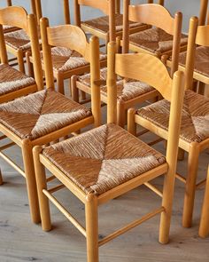 many wooden chairs with woven seats are lined up in rows on the floor next to each other