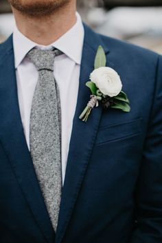 a man wearing a suit and tie with a boutonniere on his lapel