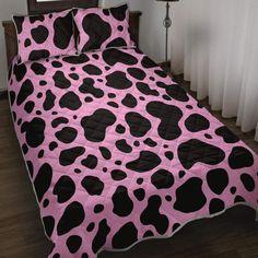 a pink and black cow print comforter on a bed