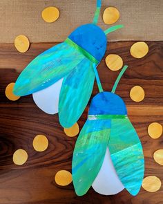 two paper bees sitting on top of a wooden table