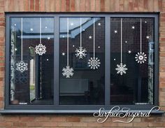 a window with snowflakes hanging from it's side and on the outside