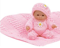 a baby doll sitting on top of a blanket with a flower in it's lap