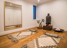 a living room with wooden floors and rugs in front of a large mirror on the wall