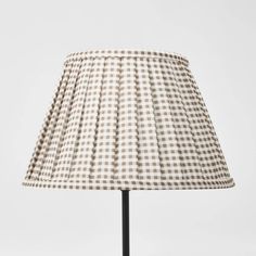 a lamp that is sitting on top of a metal stand with a white and brown checkered lampshade