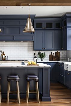 a kitchen with blue cabinets and stools next to an island in front of the sink