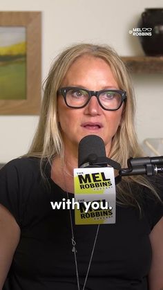 a woman with glasses is sitting in front of a microphone and holding a sign that says mel robining with you