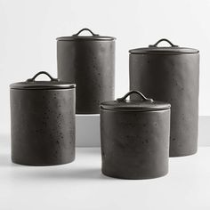 three black canisters sitting on top of a white table