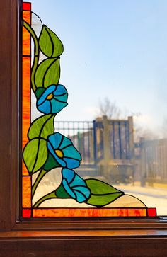 a stained glass window with blue and green flowers in the center, on a wooden frame