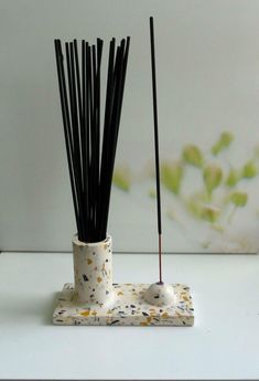 two white vases with black sticks sticking out of them on top of a table