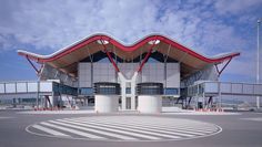 a large building with red and white stripes on it's sides, in the middle of an empty parking lot