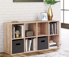 a wooden shelf with several bins and some books on it next to a white brick wall