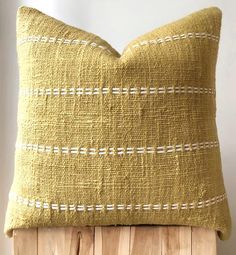 a yellow pillow sitting on top of a wooden stand