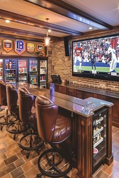 a bar with several stools in front of a large screen tv on the wall