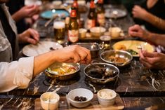 several people sitting at a table with bowls and plates of food in front of them