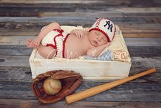 a baby is laying in a box next to a baseball glove