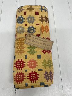 two handmade quilts are sitting on a white wooden floor, one has a tag that says table runner