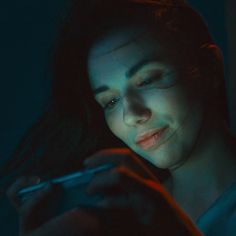 a woman is looking at her cell phone in the dark