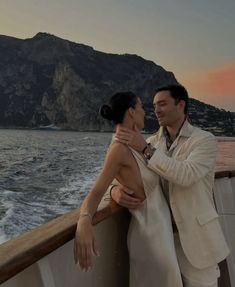 a man and woman standing on the deck of a boat looking into each other's eyes