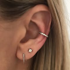 a woman wearing an ear cuff with two piercings on her left side and one in the middle