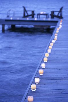 candles are lined up along the edge of a pier