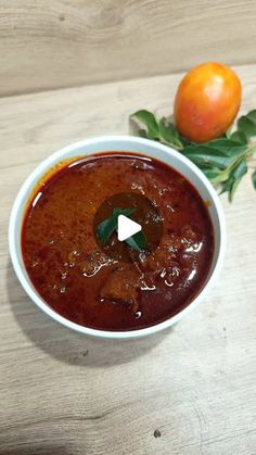 a white bowl filled with sauce next to an orange on top of a wooden table