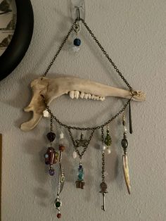 an animal skull hanging on the wall with many beads and chains attached to it's side