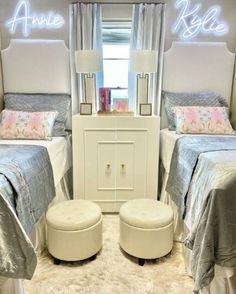 two twin beds in a small room with white furniture and lights on the wall above them