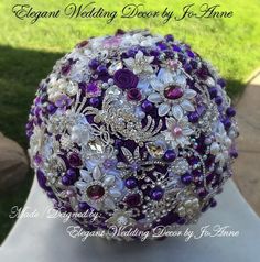 a bridal bouquet with purple and white flowers on display in front of the grass