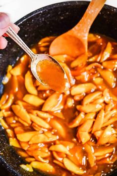 someone is spooning some food out of a skillet with the sauce on it